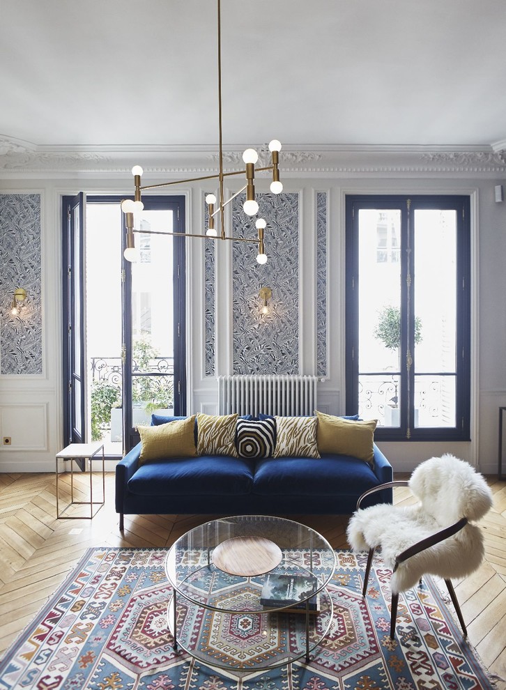 パリにあるトランジショナルスタイルのおしゃれな応接間 (青い壁、淡色無垢フローリング、ベージュの床、青いソファ) の写真