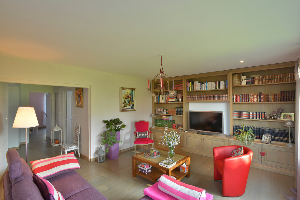 Foto di un soggiorno tradizionale con libreria, pareti beige, pavimento in legno verniciato e TV nascosta