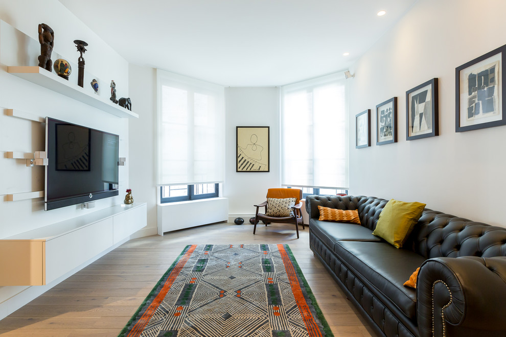 Ispirazione per un soggiorno design con pareti bianche, parquet chiaro e TV a parete
