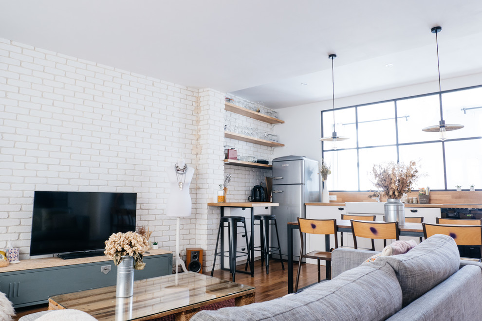 Mittelgroßes, Abgetrenntes Industrial Wohnzimmer mit weißer Wandfarbe, dunklem Holzboden und freistehendem TV in Paris