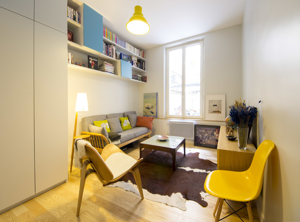 Bild på ett mellanstort skandinaviskt separat vardagsrum, med ljust trägolv, ett bibliotek och vita väggar