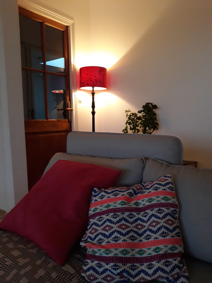 На фото: изолированная гостиная комната в современном стиле с белыми стенами, полом из терракотовой плитки, печью-буржуйкой, отдельно стоящим телевизором и коричневым полом