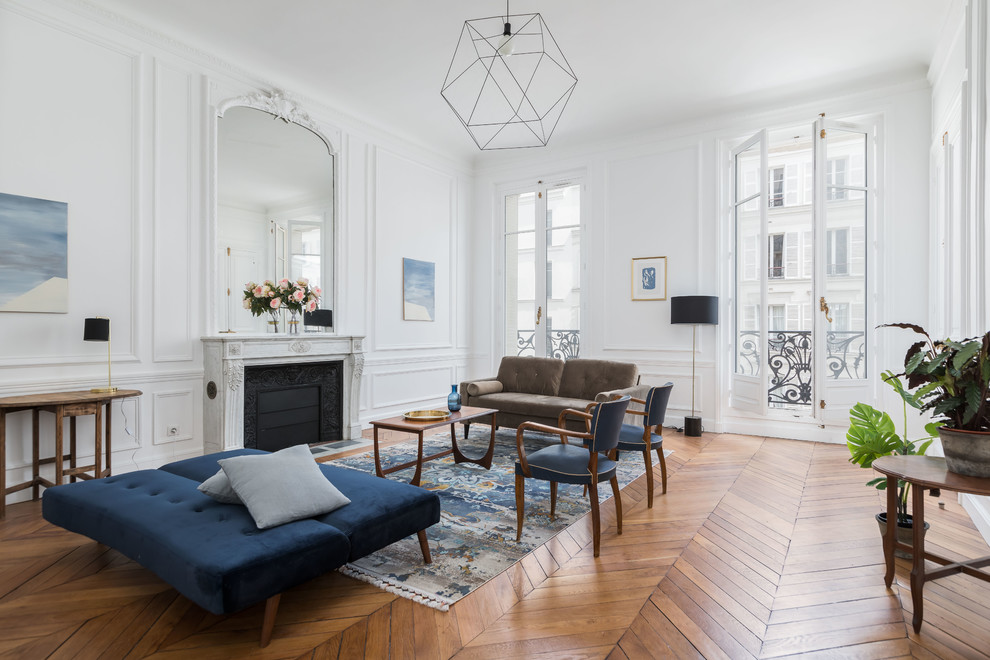 Traditional formal living room in Paris with white walls, medium hardwood flooring, a standard fireplace, no tv and feature lighting.