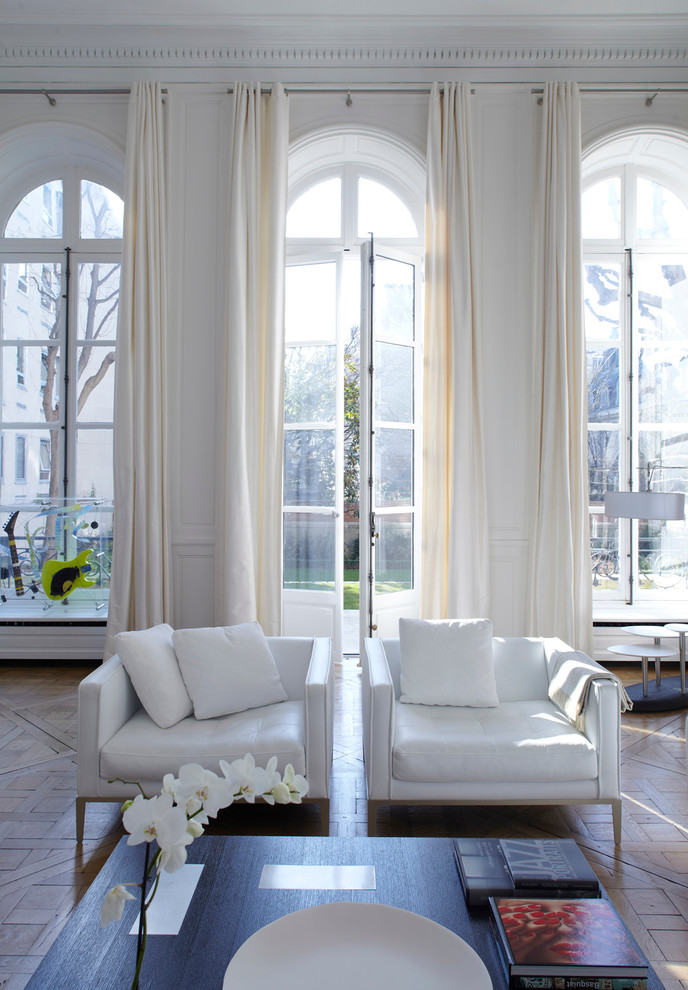 Großes, Repräsentatives, Offenes, Fernseherloses Modernes Wohnzimmer ohne Kamin mit weißer Wandfarbe und braunem Holzboden in Paris