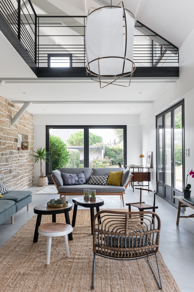 This is an example of a large scandi open plan living room in Nantes with white walls and grey floors.