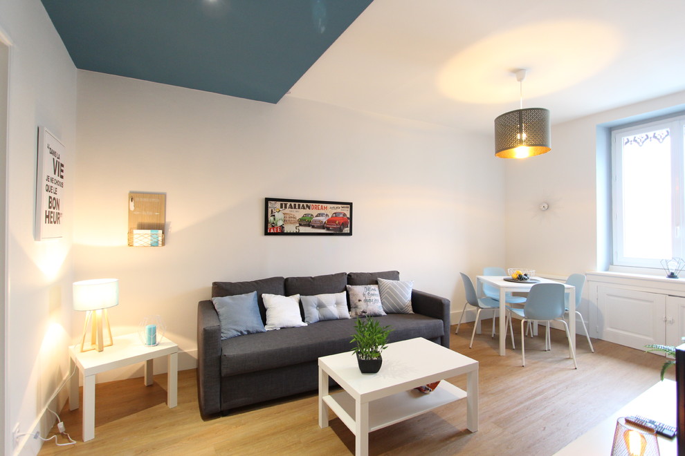 Ejemplo de salón para visitas abierto escandinavo de tamaño medio con paredes grises, suelo de madera clara, televisor independiente y suelo beige