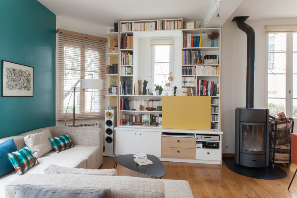 Eklektisches Wohnzimmer mit blauer Wandfarbe, braunem Holzboden, Kaminofen und braunem Boden in Paris