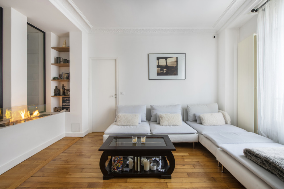 Idee per un soggiorno design di medie dimensioni e aperto con pareti bianche, pavimento in legno massello medio, camino bifacciale, nessuna TV e pavimento marrone