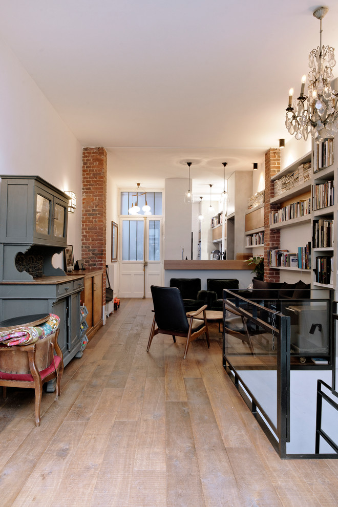 Mittelgroße, Fernseherlose Industrial Bibliothek im Loft-Stil, ohne Kamin mit weißer Wandfarbe und braunem Holzboden in Paris