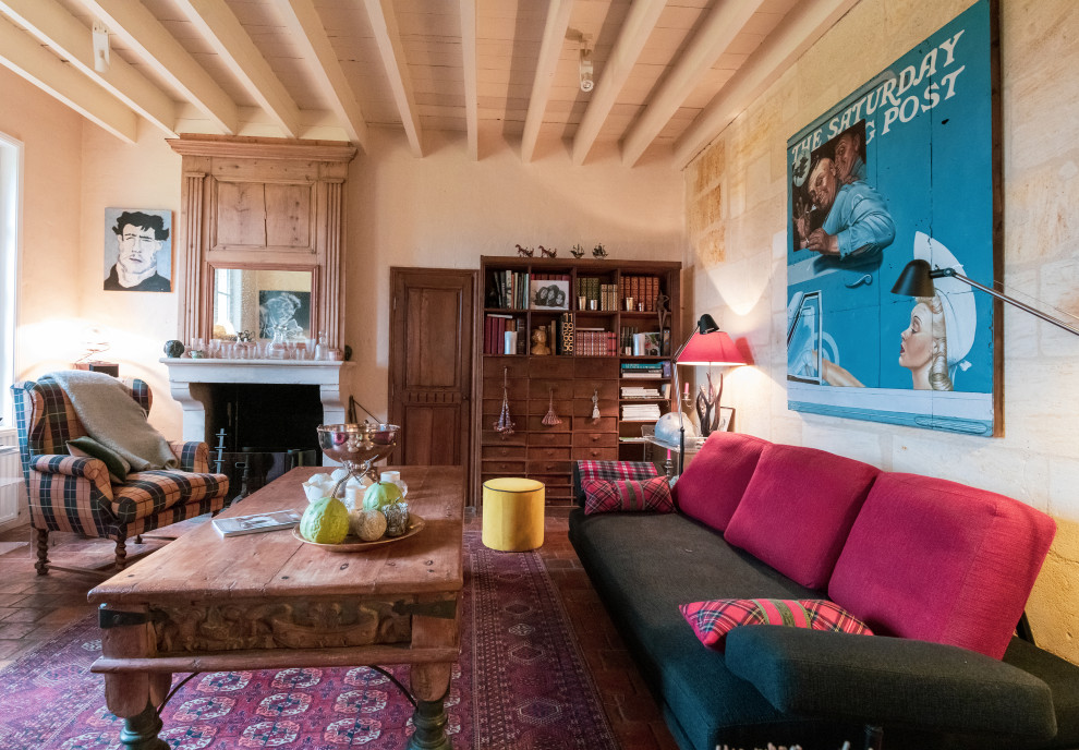 Пример оригинального дизайна: большая открытая гостиная комната в стиле кантри с с книжными шкафами и полками, бежевыми стенами, полом из терракотовой плитки, стандартным камином, фасадом камина из камня и красным полом