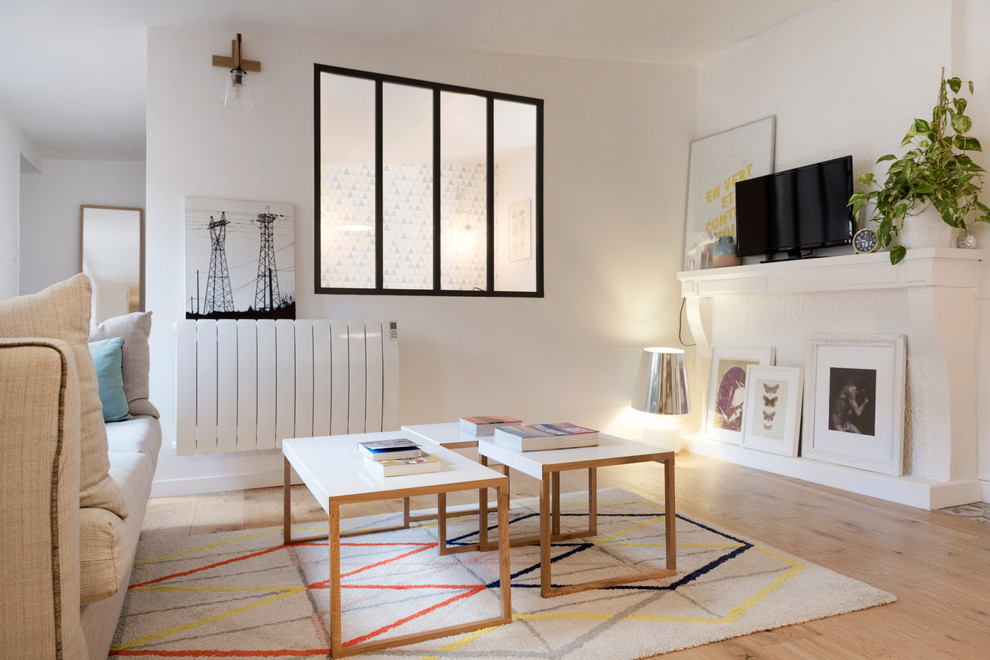 Example of a mid-sized danish open concept light wood floor and brown floor living room design in Lyon with white walls, a standard fireplace, a tv stand and a plaster fireplace