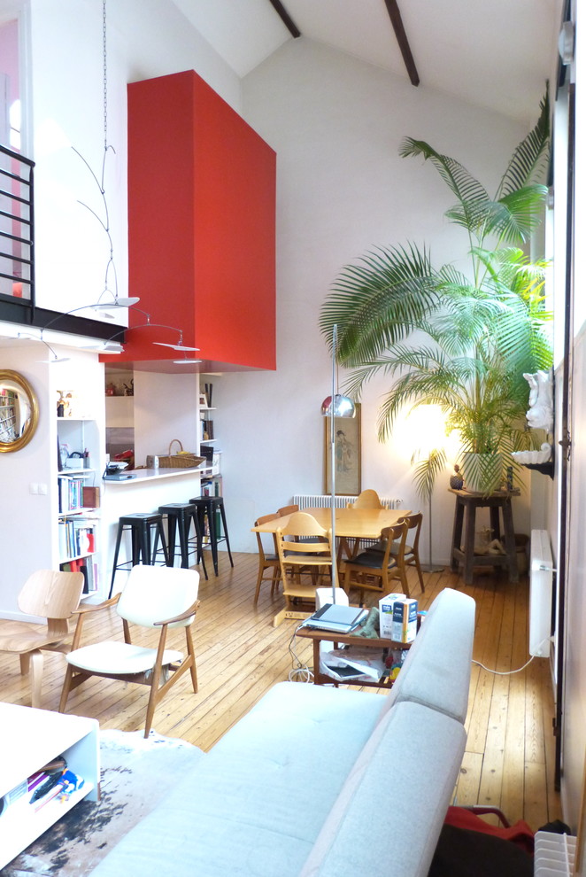 Mittelgroßes Modernes Wohnzimmer mit roter Wandfarbe, hellem Holzboden, Kamin und verputzter Kaminumrandung in Paris