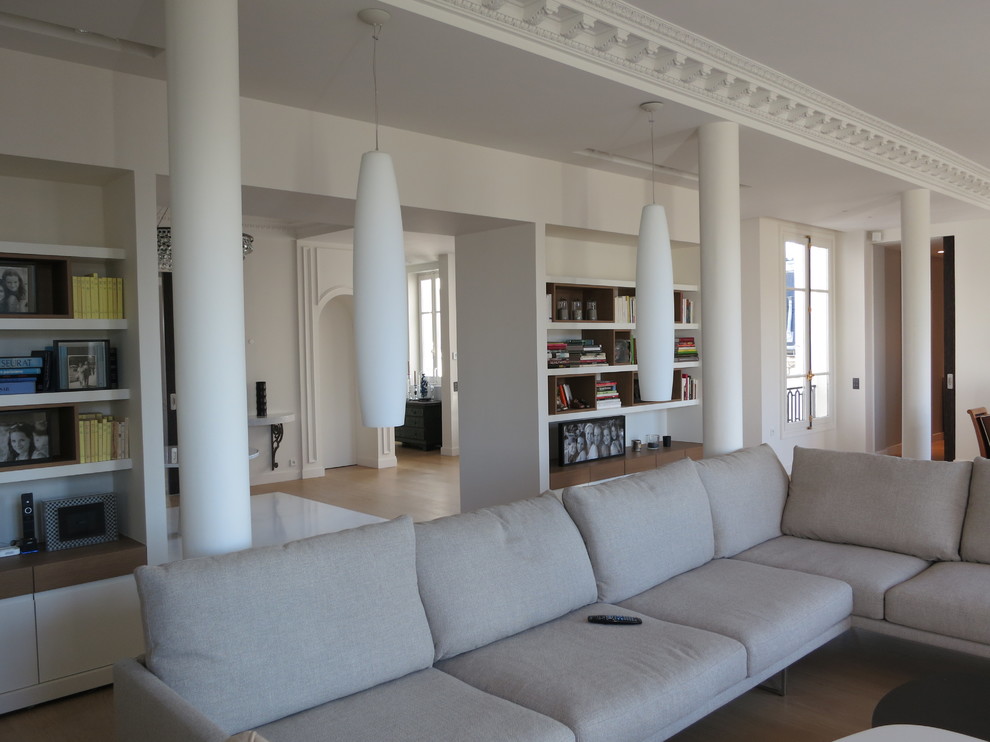 Modelo de salón abierto actual grande con paredes blancas, suelo de madera clara y suelo beige