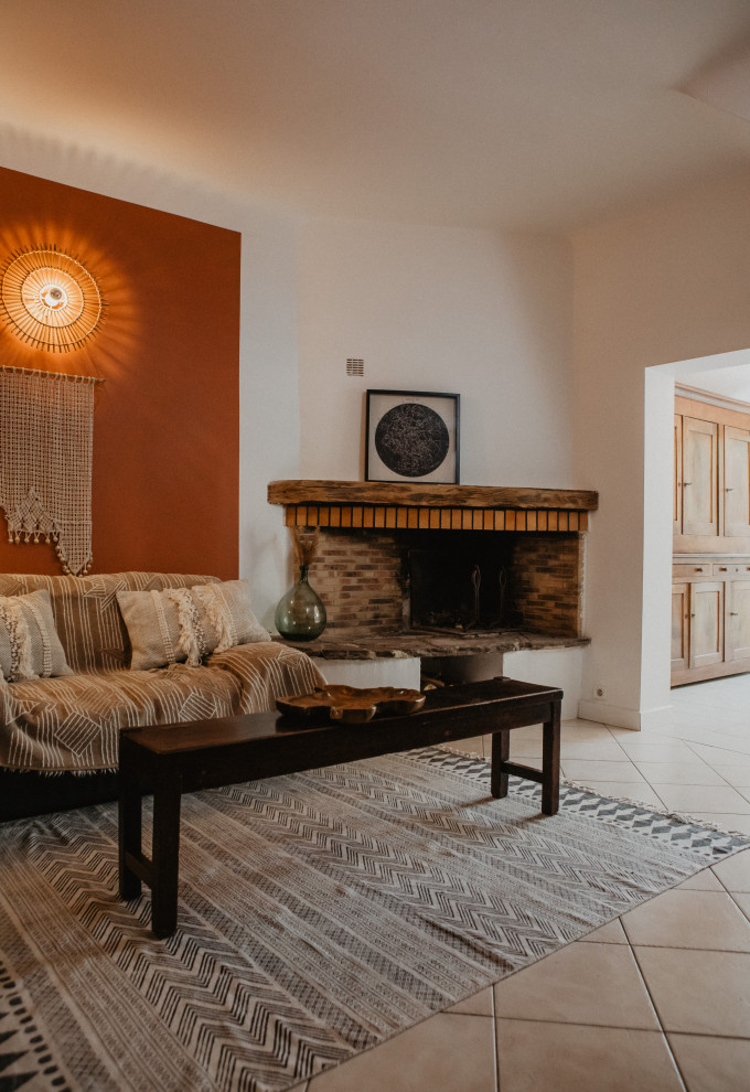 Exemple d'un salon méditerranéen ouvert avec un sol en carrelage de céramique, une cheminée d'angle, un manteau de cheminée en brique et un sol blanc.
