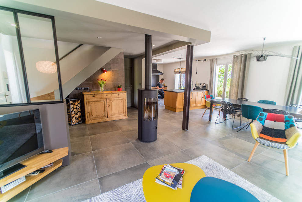 Идея дизайна: гостиная комната в современном стиле с бежевыми стенами, полом из керамической плитки, печью-буржуйкой, фасадом камина из металла и серым полом