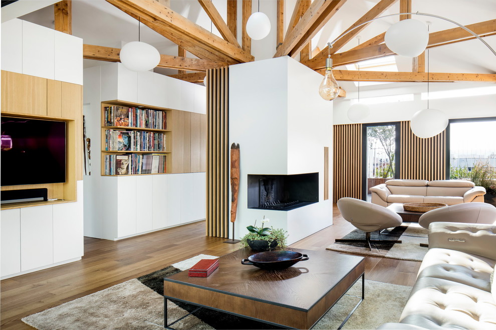 Cette photo montre un salon tendance ouvert avec une bibliothèque ou un coin lecture, un mur blanc, un sol en bois brun, une cheminée d'angle, un téléviseur fixé au mur et un sol marron.