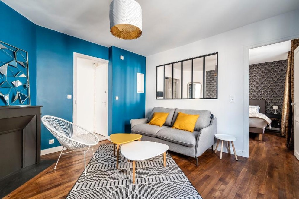 На фото: гостиная комната среднего размера в современном стиле с синими стенами, паркетным полом среднего тона, угловым камином, фасадом камина из штукатурки, телевизором на стене и коричневым полом с