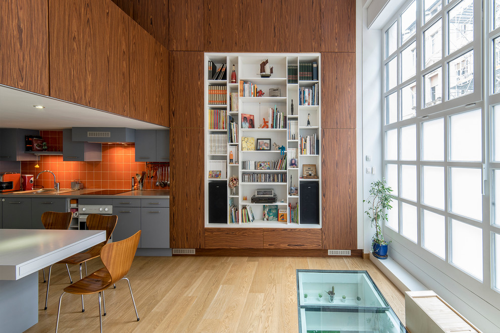 Exemple d'un salon tendance ouvert et de taille moyenne avec une bibliothèque ou un coin lecture, parquet clair et un mur marron.