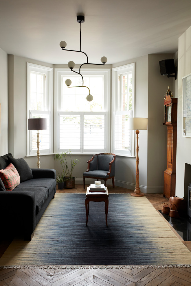 Immagine di un soggiorno vittoriano di medie dimensioni e aperto con pareti bianche, pavimento in legno massello medio, camino classico e pavimento beige