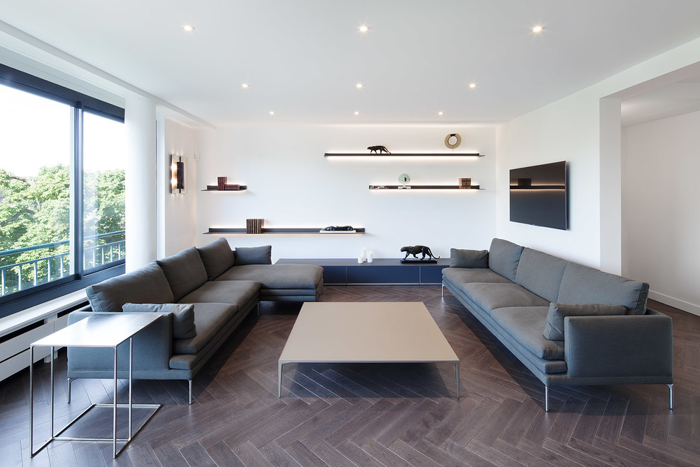 Modernes Wohnzimmer mit weißer Wandfarbe, dunklem Holzboden und TV-Wand in Paris