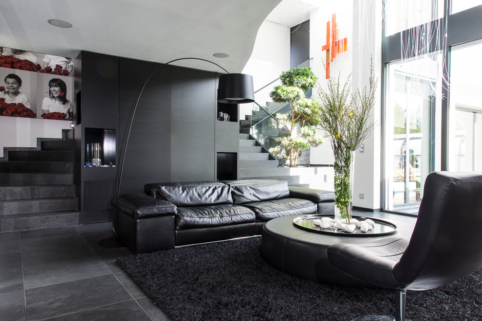 Свежая идея для дизайна: большая открытая гостиная комната в современном стиле с полом из сланца, телевизором на стене и черными стенами без камина - отличное фото интерьера