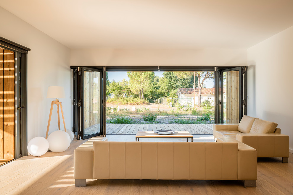 Cette image montre un salon minimaliste ouvert avec un mur blanc, un sol en bois brun, un sol marron et éclairage.