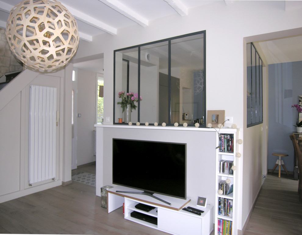 Inspiration för mellanstora klassiska allrum med öppen planlösning, med vita väggar, ljust trägolv, en fristående TV och beiget golv