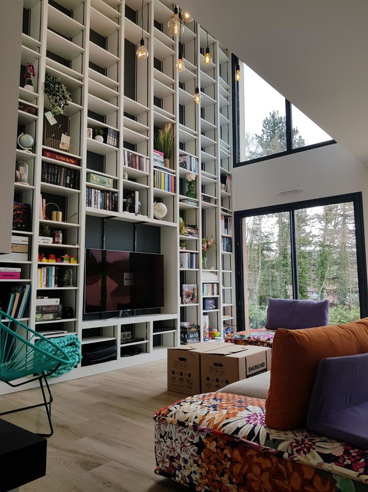 Idee per un soggiorno eclettico con libreria, pareti bianche, parquet chiaro, TV a parete e pavimento beige