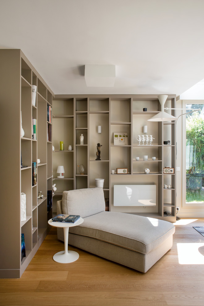 Danish open concept light wood floor and brown floor living room library photo in Paris with beige walls