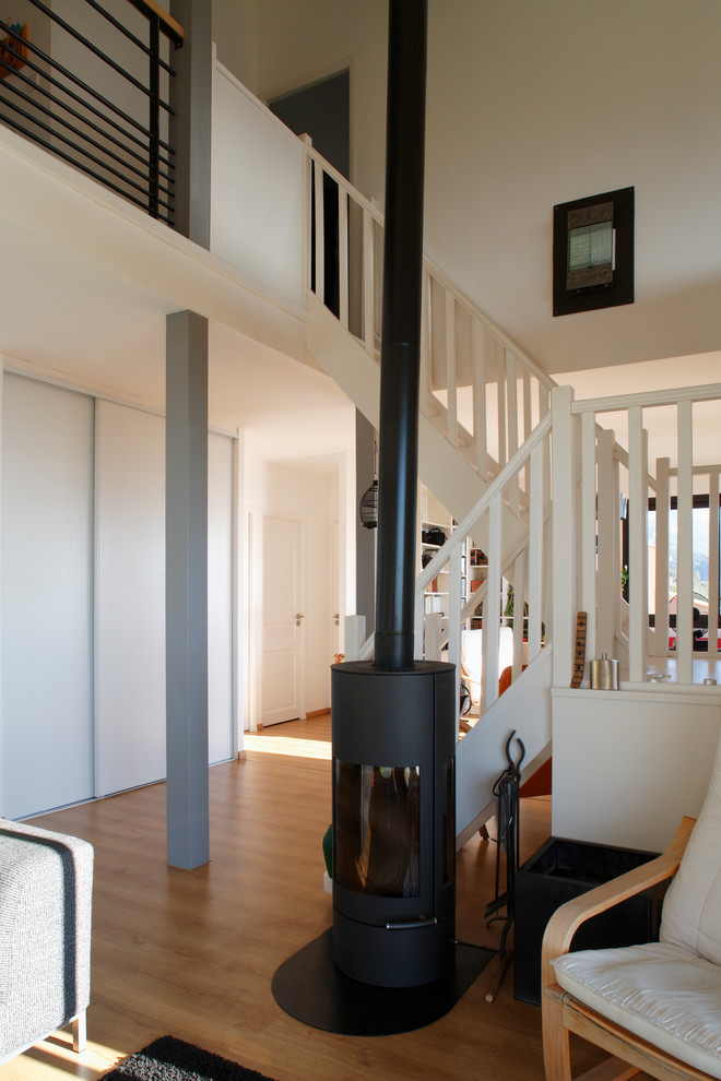 Esempio di un soggiorno contemporaneo di medie dimensioni e aperto con pareti bianche, parquet chiaro e stufa a legna