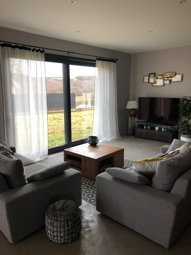 Photo of a medium sized contemporary formal open plan living room in Grenoble with a freestanding tv, grey floors, beige walls, concrete flooring and no fireplace.
