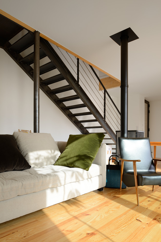 Idee per un grande soggiorno design aperto con pareti bianche, parquet chiaro, stufa a legna e nessuna TV