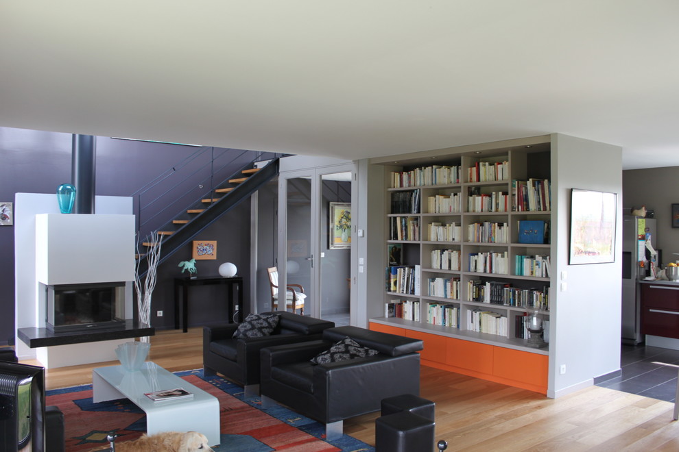 Aménagement d'un grand salon contemporain ouvert avec une bibliothèque ou un coin lecture, un mur gris, parquet clair, une cheminée standard et aucun téléviseur.