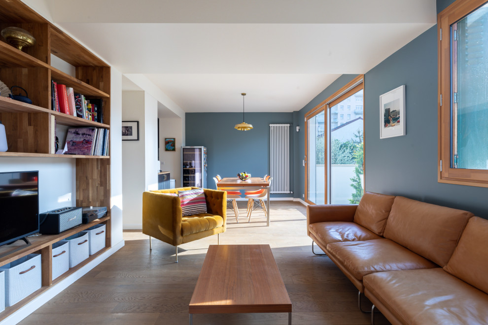 Modelo de biblioteca en casa contemporánea de tamaño medio con paredes azules, suelo de madera en tonos medios y suelo marrón