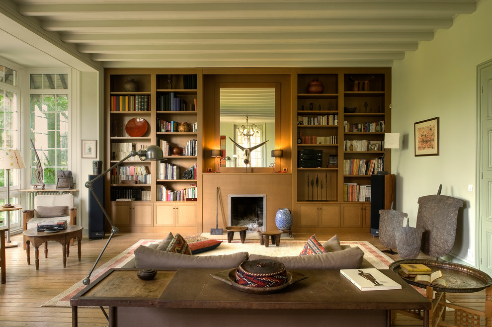 Идея дизайна: большая изолированная гостиная комната в стиле фьюжн с с книжными шкафами и полками, паркетным полом среднего тона, стандартным камином, зелеными стенами и фасадом камина из дерева без телевизора