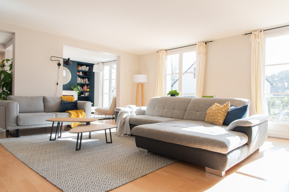 Immagine di un grande soggiorno minimalista aperto con libreria, pareti beige, parquet chiaro, nessun camino, TV autoportante e pavimento marrone