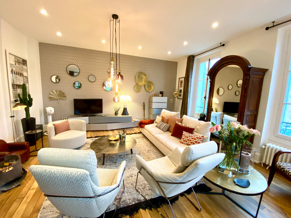 Example of a large eclectic light wood floor and wallpaper living room design in Paris with white walls, a standard fireplace and a stone fireplace