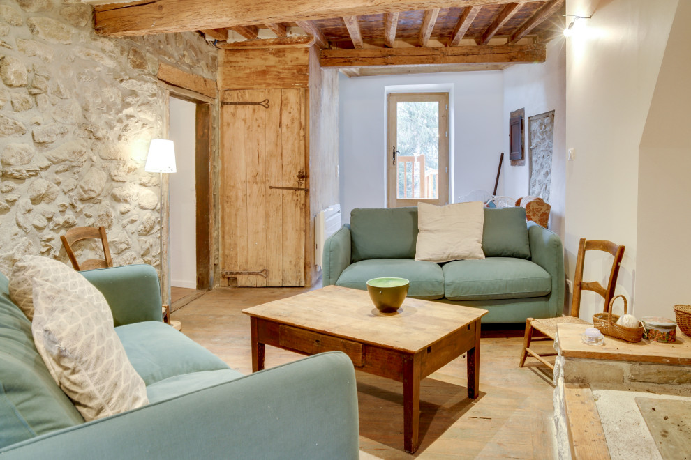 На фото: маленькая изолированная гостиная комната в стиле кантри с белыми стенами, светлым паркетным полом, стандартным камином, фасадом камина из камня и деревянными стенами без телевизора для на участке и в саду