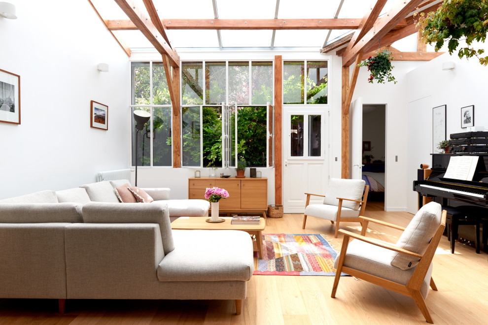 Imagen de salón para visitas abierto actual grande con paredes blancas, suelo de madera clara, vigas vistas y suelo beige