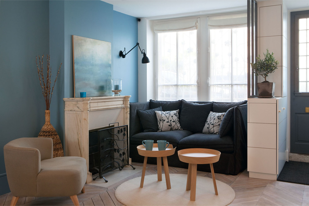 Example of a small trendy open concept light wood floor and brown floor living room design in Paris with blue walls, a standard fireplace, no tv and a stone fireplace