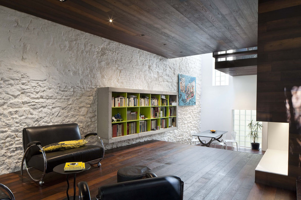 Идея дизайна: большая открытая гостиная комната в стиле модернизм с с книжными шкафами и полками, белыми стенами и темным паркетным полом без камина, телевизора