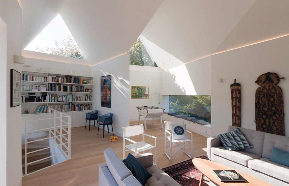 Idéer för att renovera ett stort funkis loftrum, med ett bibliotek, vita väggar och ljust trägolv