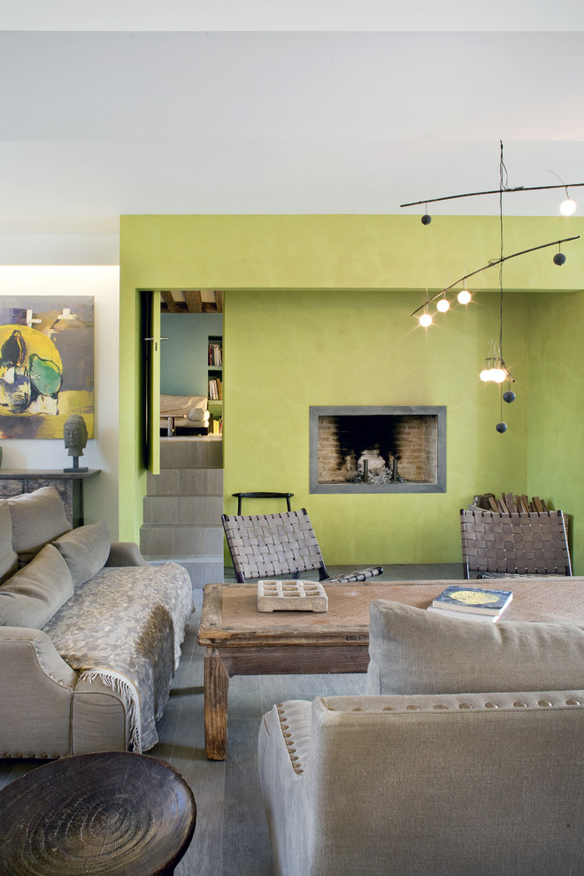 Idée de décoration pour un salon bohème ouvert avec un mur vert, une cheminée standard, sol en stratifié, un sol gris et un plafond décaissé.