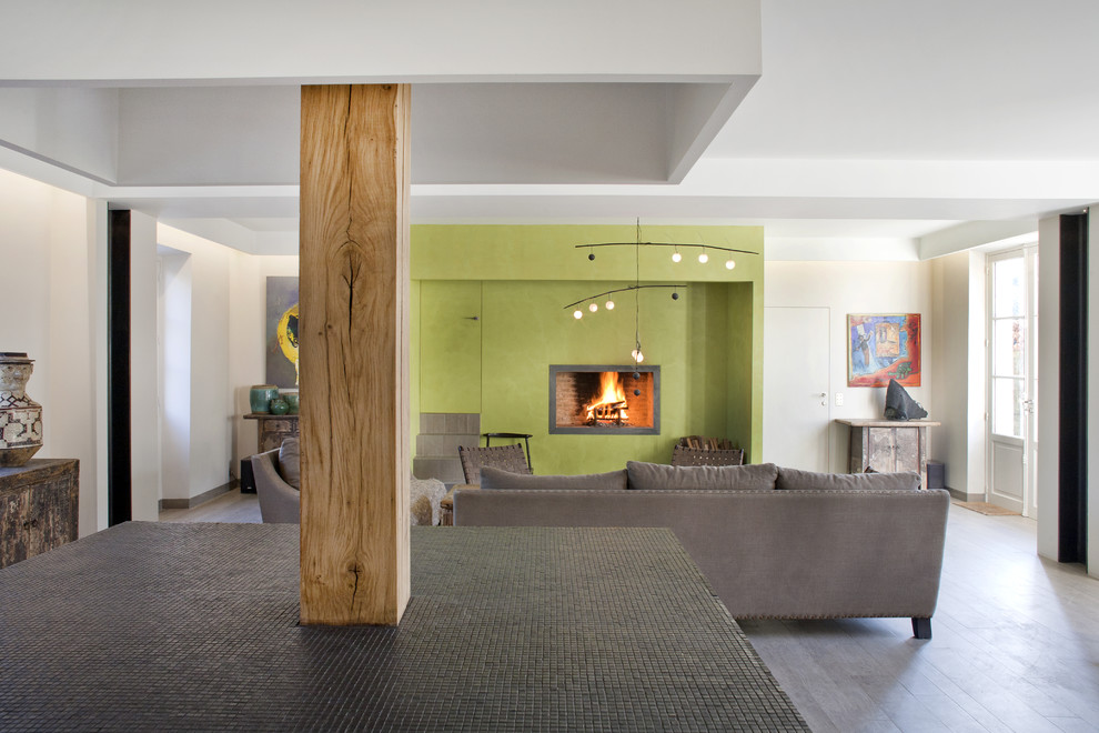 На фото: открытая гостиная комната в стиле фьюжн с зелеными стенами, полом из ламината, стандартным камином, серым полом и многоуровневым потолком с
