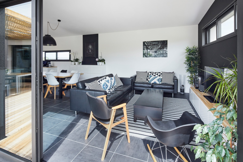 Mittelgroßes, Offenes Modernes Wohnzimmer ohne Kamin mit weißer Wandfarbe, freistehendem TV und schwarzem Boden in Nantes