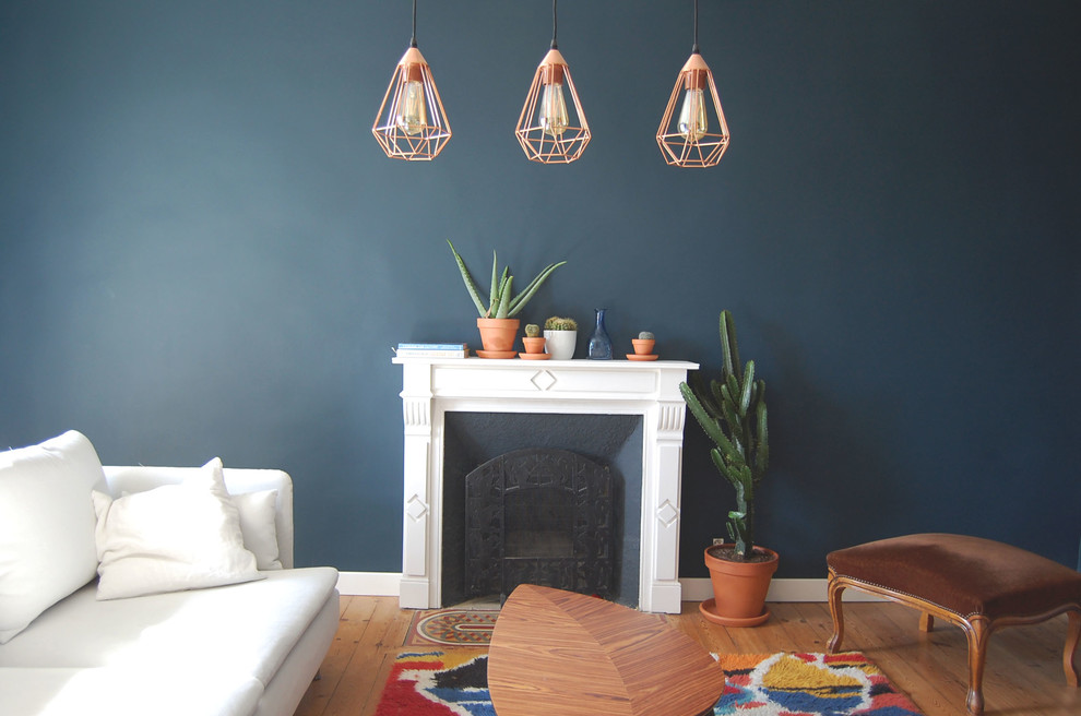 ブレストにある北欧スタイルのおしゃれな独立型リビング (青い壁、無垢フローリング、標準型暖炉、木材の暖炉まわり) の写真