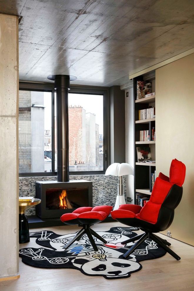 Mittelgroßes, Offenes Modernes Wohnzimmer mit grauer Wandfarbe, hellem Holzboden, Kaminofen, Kaminumrandung aus Metall und beigem Boden in Paris