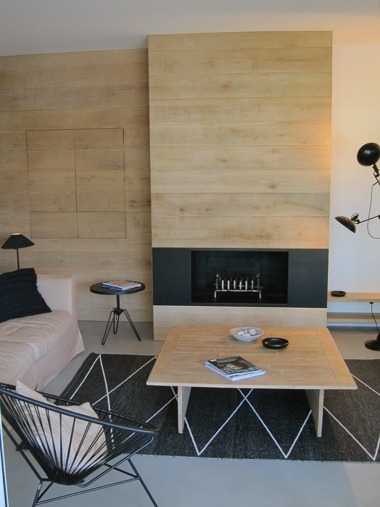 Ejemplo de salón abierto contemporáneo de tamaño medio con paredes blancas, suelo de cemento, todas las chimeneas, marco de chimenea de madera y suelo gris