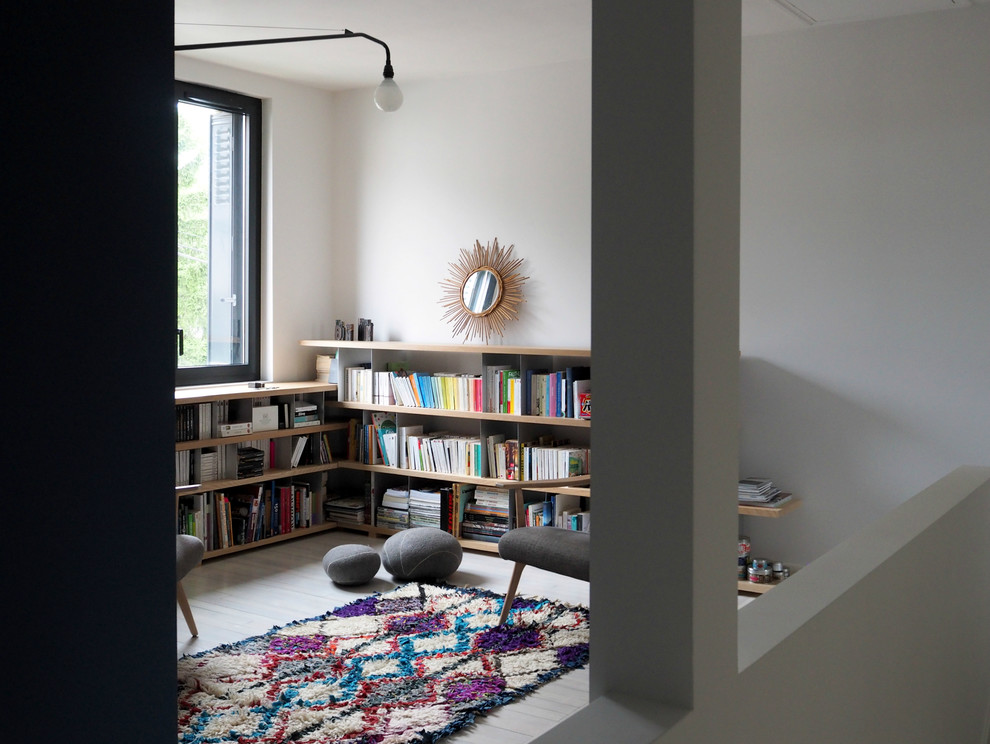 Cette photo montre un salon mansardé ou avec mezzanine tendance de taille moyenne avec une bibliothèque ou un coin lecture, un mur bleu, aucune cheminée et aucun téléviseur.