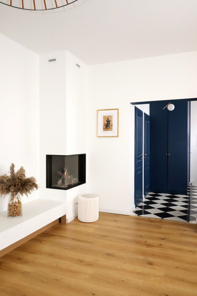 Immagine di un grande soggiorno moderno aperto con pareti bianche, pavimento in legno massello medio, stufa a legna, cornice del camino in intonaco, TV autoportante e pavimento beige